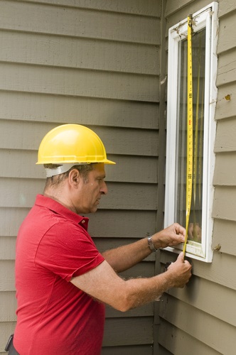 contractor carpenter measuring window for replacement repair